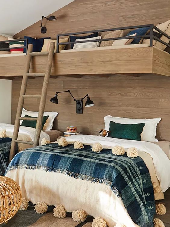 a rustic kids' room with a wood clad accent wall and bunk beds, printed bedding, black lamps is a very cozy space