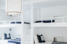 a seaside kids’ room with built-in white bunk beds with navy and white bedding, baskets for storage and a woven rug