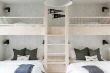 a simple and contrasting kids’ room with built-in bunk beds with white and graphite grey bedding, a ladder and a black pendant lamp
