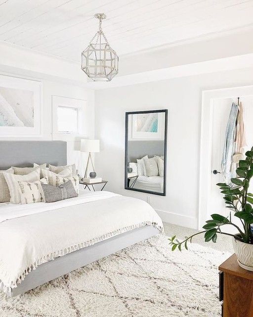 a small bedroom made in a neutral color scheme and with a mirror that make the space larger and more welcoming