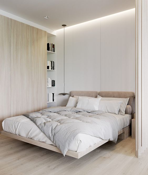 A small bedroom made larger with a neutral color scheme, with built in lights and floor to ceiling shelves