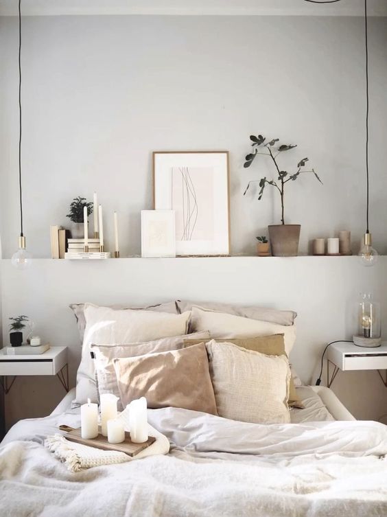 A small bedroom with a built in shelf over the bed that visually widens the room, a neutral color scheme makes it bigger