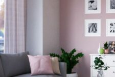 a stylish Scandinavian living room with a pink accent wall, a large grey sectional, white furniture and a gallery wall
