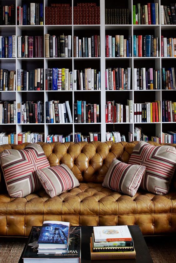 a stylish bookcase that takes the whole wall and a brown leather sofa plus a simple coffee table