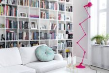a stylish modern library with a large built-in bookcase, white furniture and a whimsy hot pink floor lamp