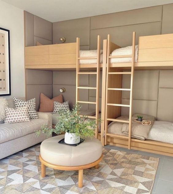 a stylish neutral kids' room with a grey upholstered bed, built-in bunk beds and neutral bedding, a grey sofa and an ottoman