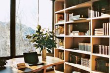 a super stylish modern home library with a cool bookshelf unit, a wooden desk and a whimsy chair plus a gorgeous view