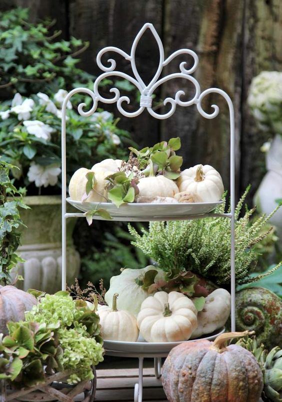 a tiered stand with natural pumpkins and greenery is a perfect farmhouse decoration for the fall