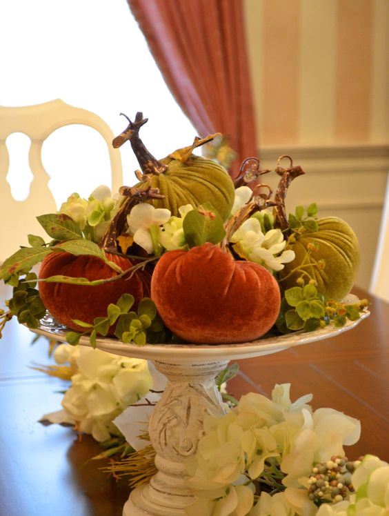 a vintage white stand with bright velvet pumpkins, blooms and leaves is a chic vintage rustic centerpiece