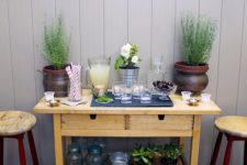 an IKEA Forhoja cart used as a storage piece for outdoors and an outdoor bar with potted greenery and soem lemonade