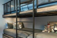 an industrial kids’ bedroom with built-in bunk beds of blackened steel and wood, with storage drawers and grey and blue bedding