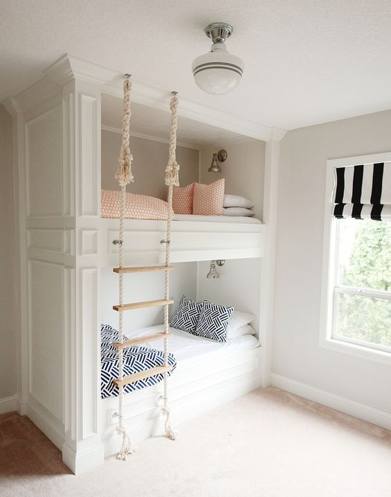 Built in bunk beds with a rope ladder hanging from the ceiling make up a cozy and cute space for sleeping