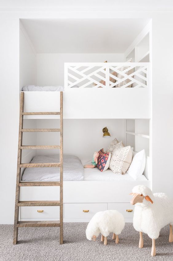 built-in white bunk beds with a wooden ladder, catchy railing, wall lamps and storage drawers in the lower bed