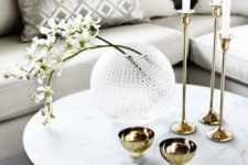 gold bowls, candles in gold tall candleholders and a glass bubble vase with fresh white blooms