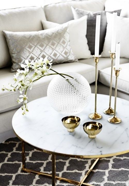 gold bowls, candles in gold tall candleholders and a glass bubble vase with fresh white blooms
