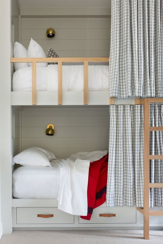 grey bunk beds with a ladder, storage drawers and wall lamps plus gingham curtains to keep privacy