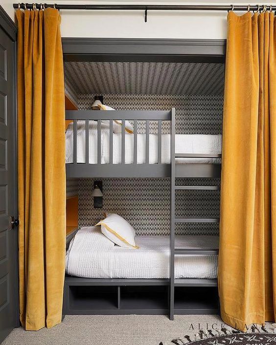 grey bunk beds with a mathcing ladder and storage psace under the bed, mustard curtains and wall lamps over the beds