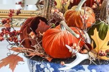lots of bright velvet pumpkins, berries, antlers and faux leaves in a blue handpainted bowl for a bold centerpiece