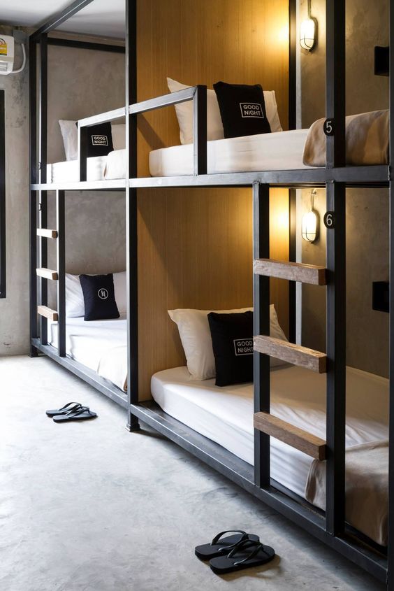 stylish industrial bunk beds of metal and wood, with wall lamps and ladders to reach each upper bed