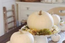 white pumpkins with fall leaves and berries plus some white pumpkins on the table for a centerpiece