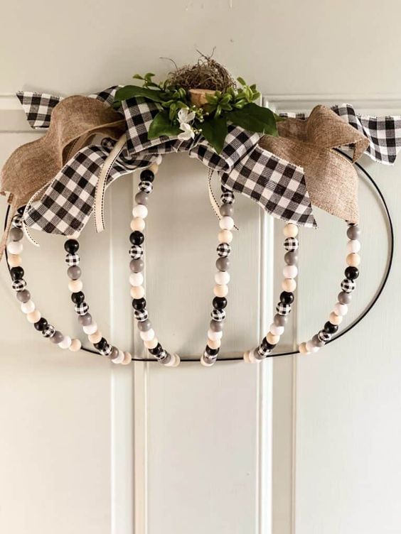 a Thanksgiving door hanger of plaid and neutral beads, a burlap and plaid bow, greenery and hay is a lovely decor idea
