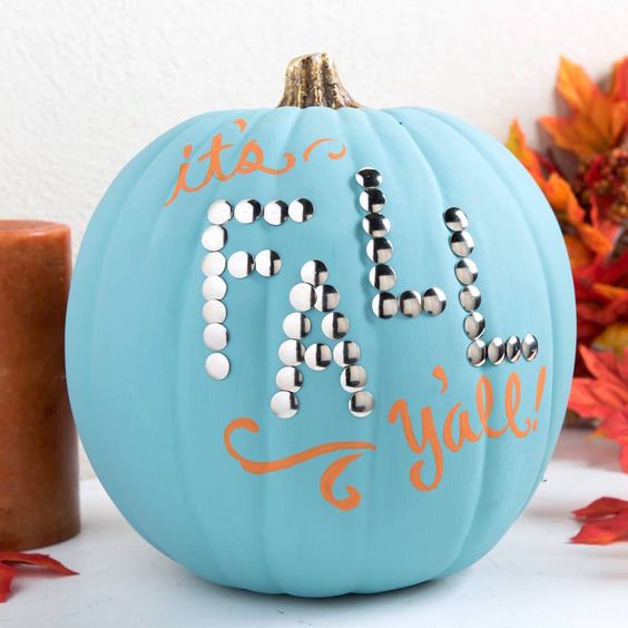 a blue pumpkin decorated with orange letters and some decorative nails for fall and Thanksgiving
