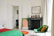 a bold bedroom with a fireplace clad with black marble, a bed with colorful bedding, a bold green chair and an artwork, a ceiling with molding