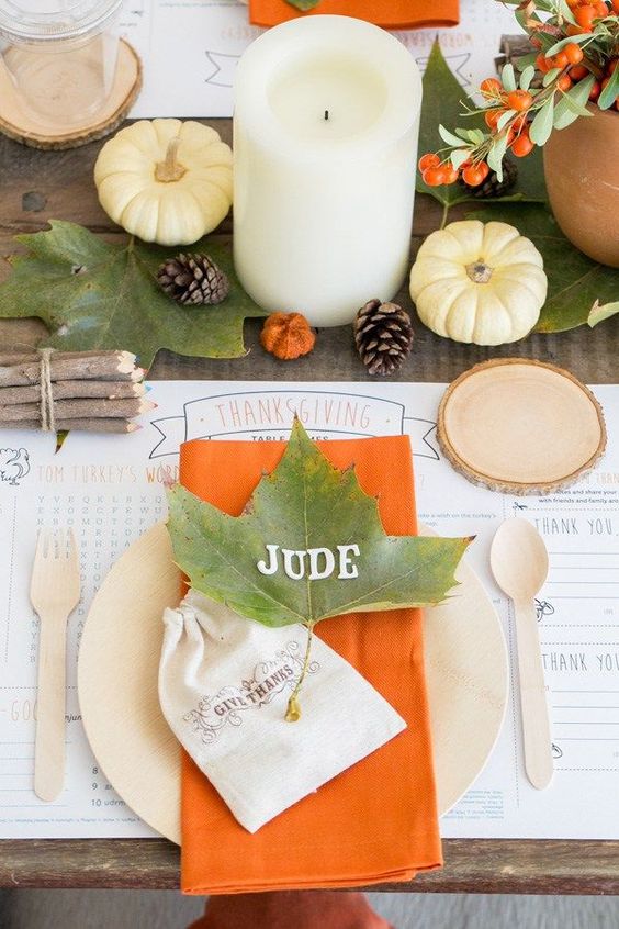 a bright and simple Thanksgiving table with fall leaves, berries, pumpkins, pillar candles and touches of orange