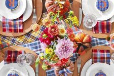 a colorful Thanksgiving tablescape with bright plaid table runners and napkins, plaid embroidery hoops, bright flowers and plaid pumpkins