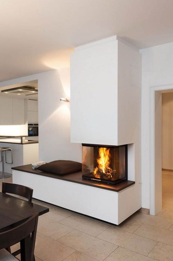 A contemporary fireplace with a bench to enjoy it and a glass cover to make the fire all visible