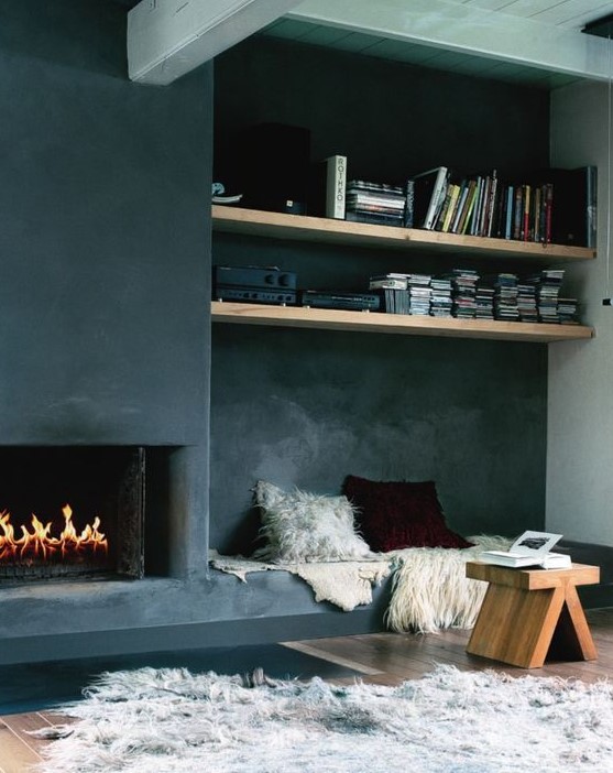 A contemporary space with a built in fireplace with a screen and a bench with pillows built in next to the fireplace