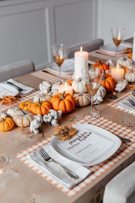 a cozy and bright fall centerpiece of white and orange pumpkins, pillar candles and cotton