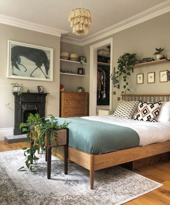 a cozy bedroom with grey walls, a firpelace, stained furniture, potted plats and a fringe chandelier is lovely