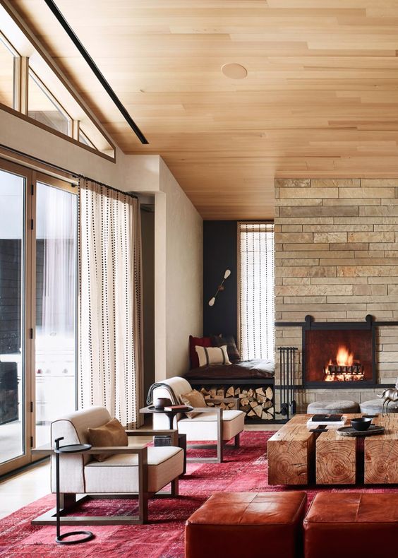 A cozy farmhouse space with a brick clad fireplace, a built in seat with pillows and firewood storage