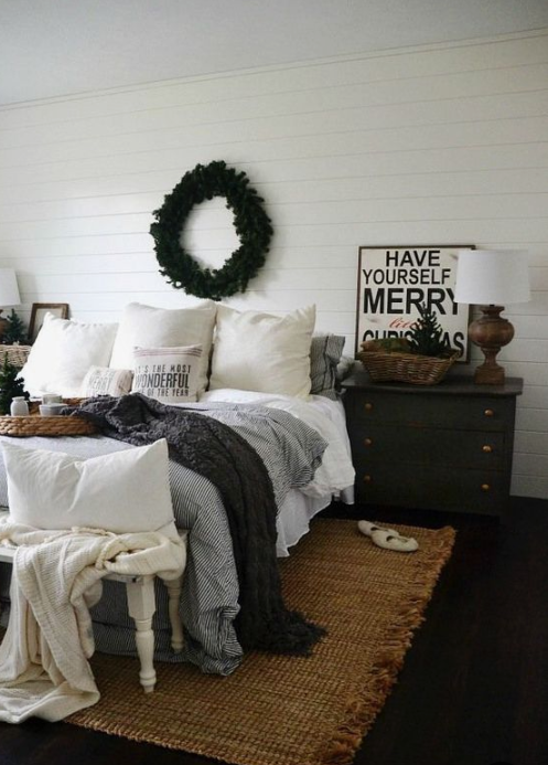 a cozy wintry bedroom with knit blankets, an evergreen wreath, a Christmas tree feels veyr cozy and chic