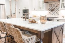 a fabulous vintage kitchen with white cabinets, a stained kitchen island with vintage legs, chic pendant lamps and woven stools