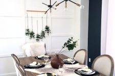 a laconic Thanksgiving tablescape with a eucalyptus arrangement, little white pumpkins, black plates and a fau fur runner