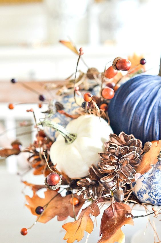 a lush Thanksgiving centerpiece of faux pumpkins, fall leaves berries, acorns and pinecones