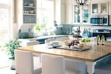 a lvoely kitchen with vintage touches, with shaker and planked cabinets, a large kitchen island with elegant white stools and a crystal chandelier