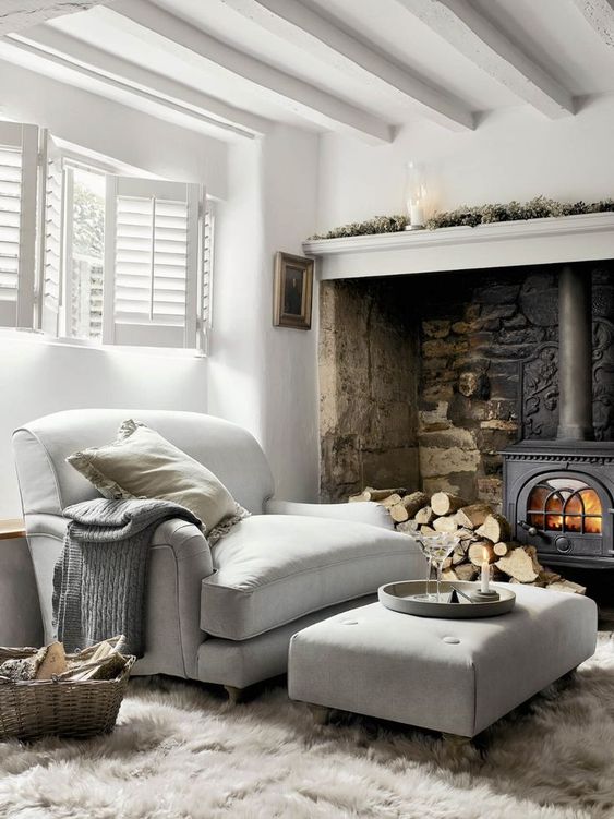 a metal hearth and firewood, a large double chair and a matching ottoman make up a welcoming and cool nook