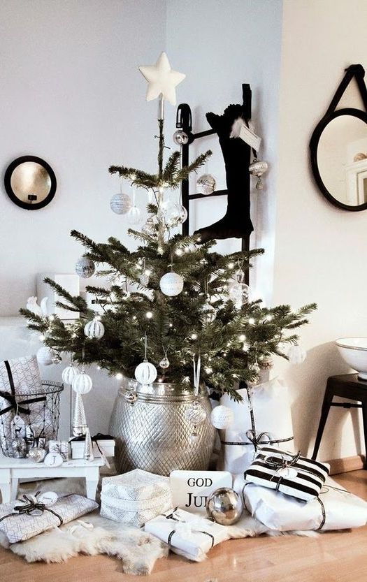 a modern Scandinavian Christmas tree with white ornaments, lights and a silver metallic tree skirt is a stylish idea