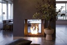 a modern double-sided fireplace done of grey concrete looks really spectacular and very chic