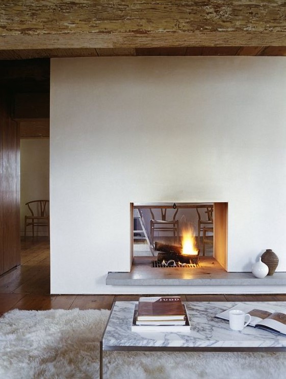 A modern white double sided fireplace with a concrete stand is a cozying up and chic idea for a modern space