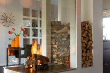 a modern white fireplace with a glass cover and firewood storage is a nice space divider and is a very cozying up piece