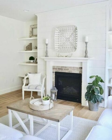 a neutral farmhouse fireplace nook with a brick clad fireplace, a white chair with a pillow is a welcoming space to spend time