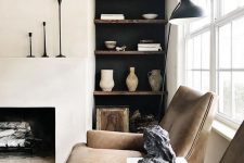 a soothing living room with a built-in fireplace, built-in shelves and brown leather chairs, some black touches