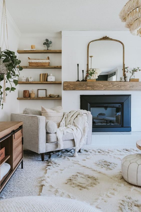 A welcoming farmhouse nook with a built in fireplace and a wooden mantel, a neutral chair with pillows and built in shelves