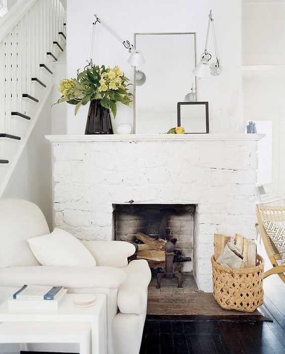 a welcoming farmhouse nook with a white brick clad fireplace, a creamy chair and tables plus a basket for storage