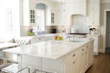 a white farmhouse kitchen with shaker style cabinets, a shiny backsplash, a large kitchen island with an eating space and acrylic stools