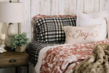 faux fur blankets, plaid bedding, a wooden wreath and potted greenery make the bedroom winter-like and cozy